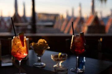 Aperol Spritz at sunset at a beach cafe with sun umbrellas in the background