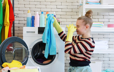 Smiling young Caucasian female Wear yellow rubber gloves for clean of housework in laundry room....