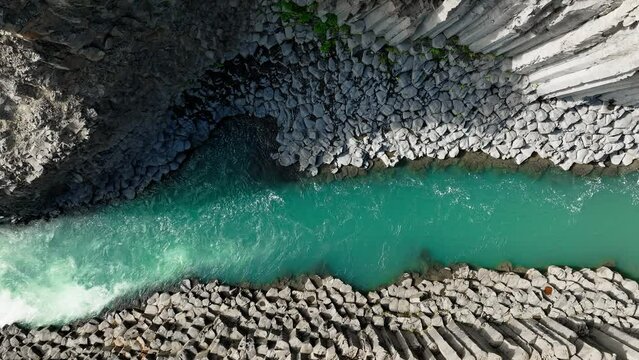 Majestic turquoise river running through unique white rock formations, directly above aerial shot. Canyon, ravine, nature, and Iceland concept.