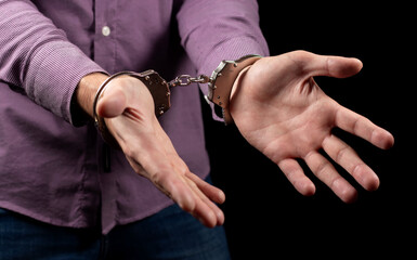 Businessman in handcuffs arrested for financial fraud, sitting in interrogation room