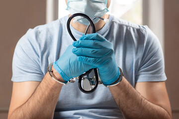 A medical officer, doctor, or quack in a blue medical uniform in handcuffs.