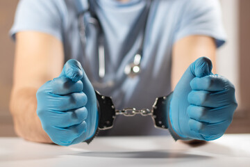 Doctor handcuffed, hands close-up, concept of medical corruption, bribery, crime