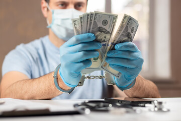 A doctor with dollar bank notes and handcuffs. concept of medical corruption, bribery, crime
