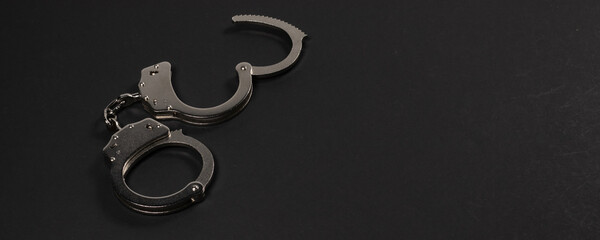 Shiny metal handcuffs on the dark table