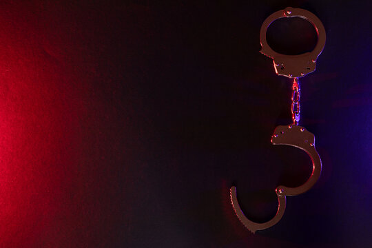 Silhouette of handcuffs. Image with the flashing red and blue police lights dark background.