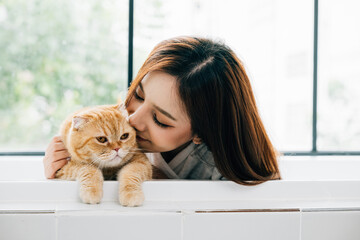 Sunlit bathroom serenity, An attractive girl relaxes in the tub with her Scottish Fold cat,...