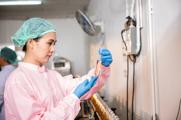 At juice beverage factory woman food engineer conducts food quality and safety testing using test...