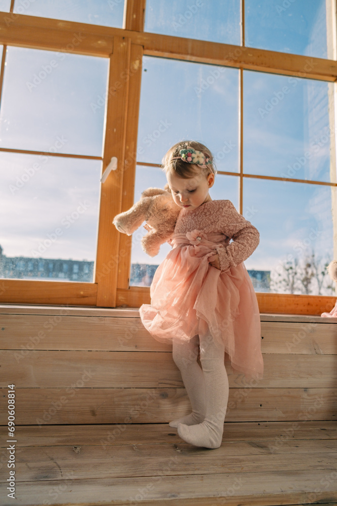 Poster little cute girl in dress near window