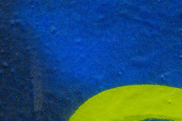 Close-up of a blue spray painted uneven wall with a yellow shape. Abstract full frame textured...