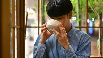 Cropped image of a Young Asian man drinking Japanese traditional matcha tea, The concept of...