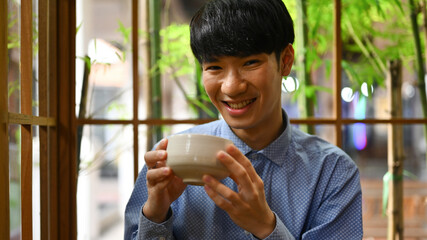 Close up with A Happy Young Asian man enjoying Japanese traditional matcha tea, The concept of...