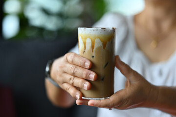 Close-up with mature adult woman hands holding an iced coffee latte