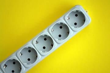 White electrical multi plug extender with european socket on bright yellow background close up
