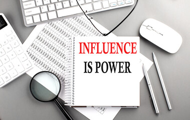 INFLUENCE IS POWER text on notepad on chart with keyboard and calculator on grey background