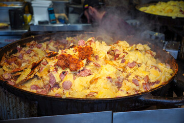 hot pan of street food at market. sausage with potato and cheese. tasty food 