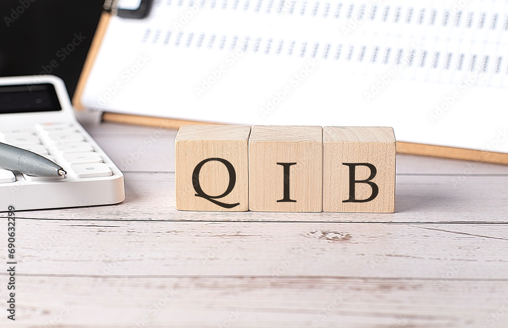Poster qib word on a wooden block with clipboard and calculator