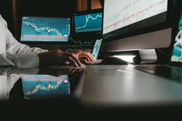 Close-up of male trader typing on computer keyboard while trading on stock market in night office