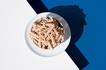 Espirales de pasta. Macarrones de trigo orgánico sobre fondo azul. Vista superior