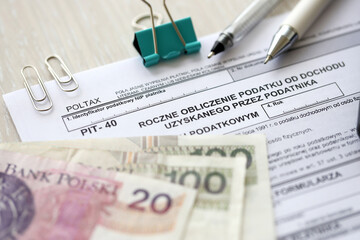 Annual calculation of tax on income obtained by taxpayer, PIT-40 tax forms on accountant table with pen and polish zloty money bills close up
