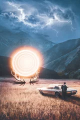 Fotobehang A man laying against his classic sport car in a field at a stormy evening and a mountain behind. a very bright glowing big fire portal gate is opened from some deer horns and its swirling and burning © MeSSrro