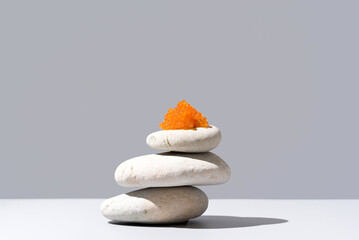 Caviar de salmón sobre piedras blancas. Comida gourmet sobre fondo gris - obrazy, fototapety, plakaty