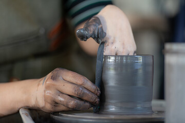 hands of a potter, creating an earthen jar on the pottery wheel