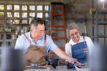 Portrait of a senior Asian couple doing activities together in the pottery workshop.