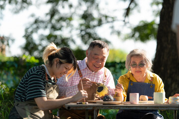 In the pottery workshop, an Asian retired couple is engaged in pottery making and clay painting activities.