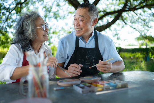 In the pottery workshop, an Asian retired couple is engaged in pottery making and clay painting activities.