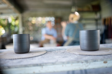 Teacher and seniors student doing activities together in the pottery workshop, Pottery cup foreground