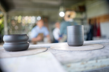Teacher and seniors student doing activities together in the pottery workshop, Pottery cup foreground