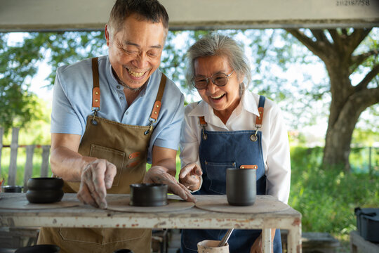 Portrait of a senior Asian couple doing activities together in the pottery workshop.