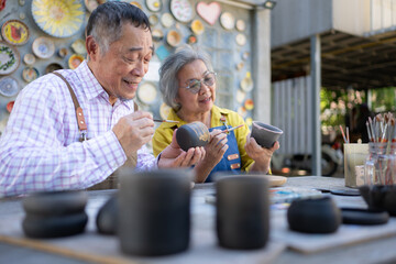 In the pottery workshop, an Asian retired couple is engaged in pottery making and clay painting activities.
