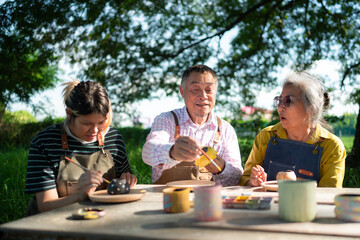 In the pottery workshop, an Asian retired couple is engaged in pottery making and clay painting activities.