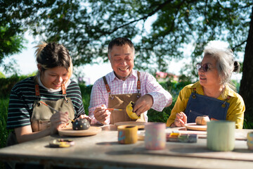In the pottery workshop, an Asian retired couple is engaged in pottery making and clay painting activities.