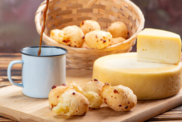 Cheese bread and cheese, a table with cheese bread and pieces of cheese and a cup of coffee on a rustic table, selective focus.
