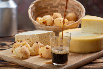 Cheese bread and cheese, a table with cheese bread and pieces of cheese and a glass of coffee on a rustic table, selective focus.