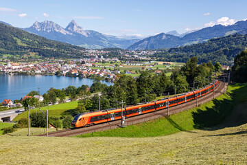 Passenger train type Stadler Flirt of Südostbahn at Grosser Mythen mountain at Lake Zug in the Swiss Alps in Arth, Switzerland