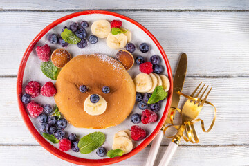 Funny and cute Christmas teddy bear pancakes on a red white plate decorated with fresh berry, fruit and powdered sugar, children's Christmas breakfast or brunch idea - Powered by Adobe