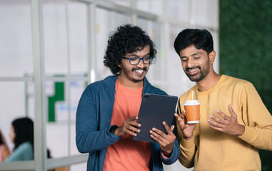 Two happy Colleges or coworkers at office discussing from tablet during break time - concept of...