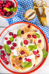 Sweet cranberry pancakes for winter breakfast or brunch. Festive Christmas, New Year breakfast dessert with vanilla creamy topping and fresh cranberries, copy space