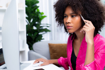 Working African woman blogger concentrated on the laptop screen with serious face, searching...