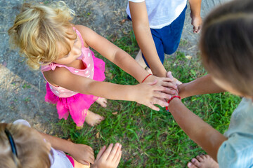 Fototapeta premium a group of children stand together in a circle and fold their hands, team spirit before the game.
