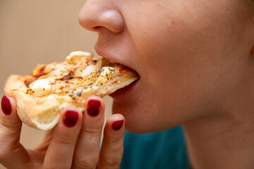 Closeup of woman eating slice of pizza