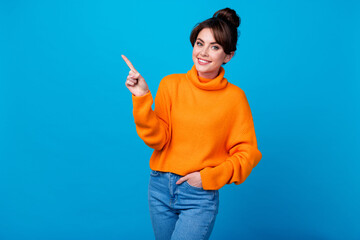 Photo of adorable excited lady wear knitted pullover pointing finger empty space isolated blue...