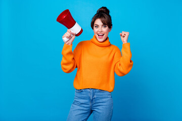 Photo of lucky excited woman dressed orange sweater rising fist announcing sale isolated blue color...