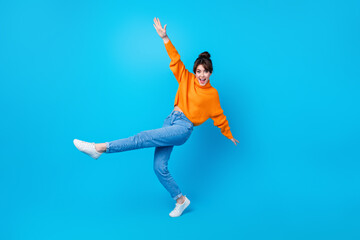 Full length photo of excited carefree woman dressed orange sweater dancing having fun isolated blue...