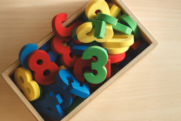 Top view of wooden box filled with colorful numbers, used for children learning