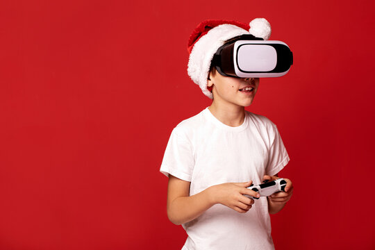 Fascinated little boy in santa claus red hat using VR virtual reality goggles.
