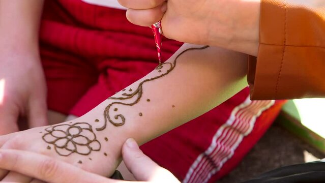 Hand Held Close Up Shot of Artist Drawing Floral Patterns on Hand with Henna